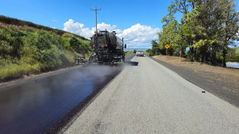 Máquina vibroacabadora aplica asfalto em obra de rodovia