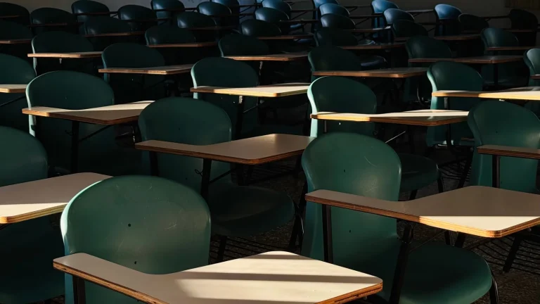 Sala de aula vazia com carteiras iluminadas pelo sol