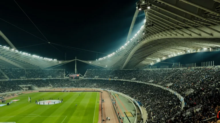 Estádio de futebol iluminado à noite com torcida