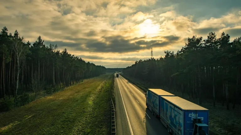 Caminhões trafegam em rodovia ao pôr do sol